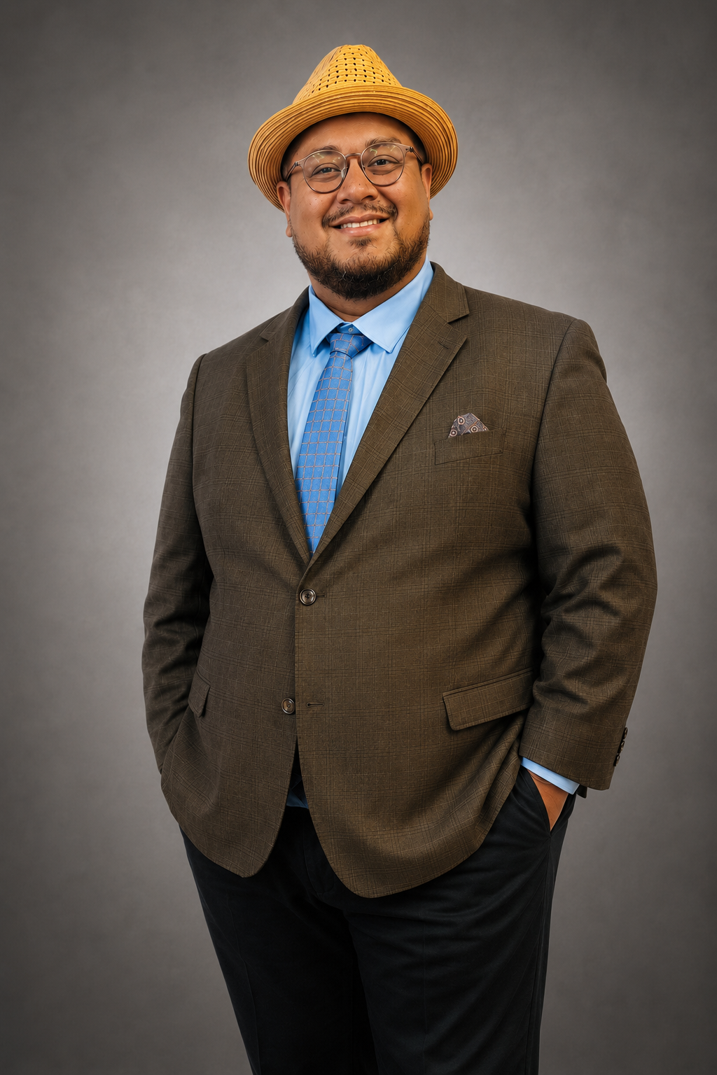 Studio portrait of Dr. Angel L. Velez in a straw hat, brown suit, and blue tie