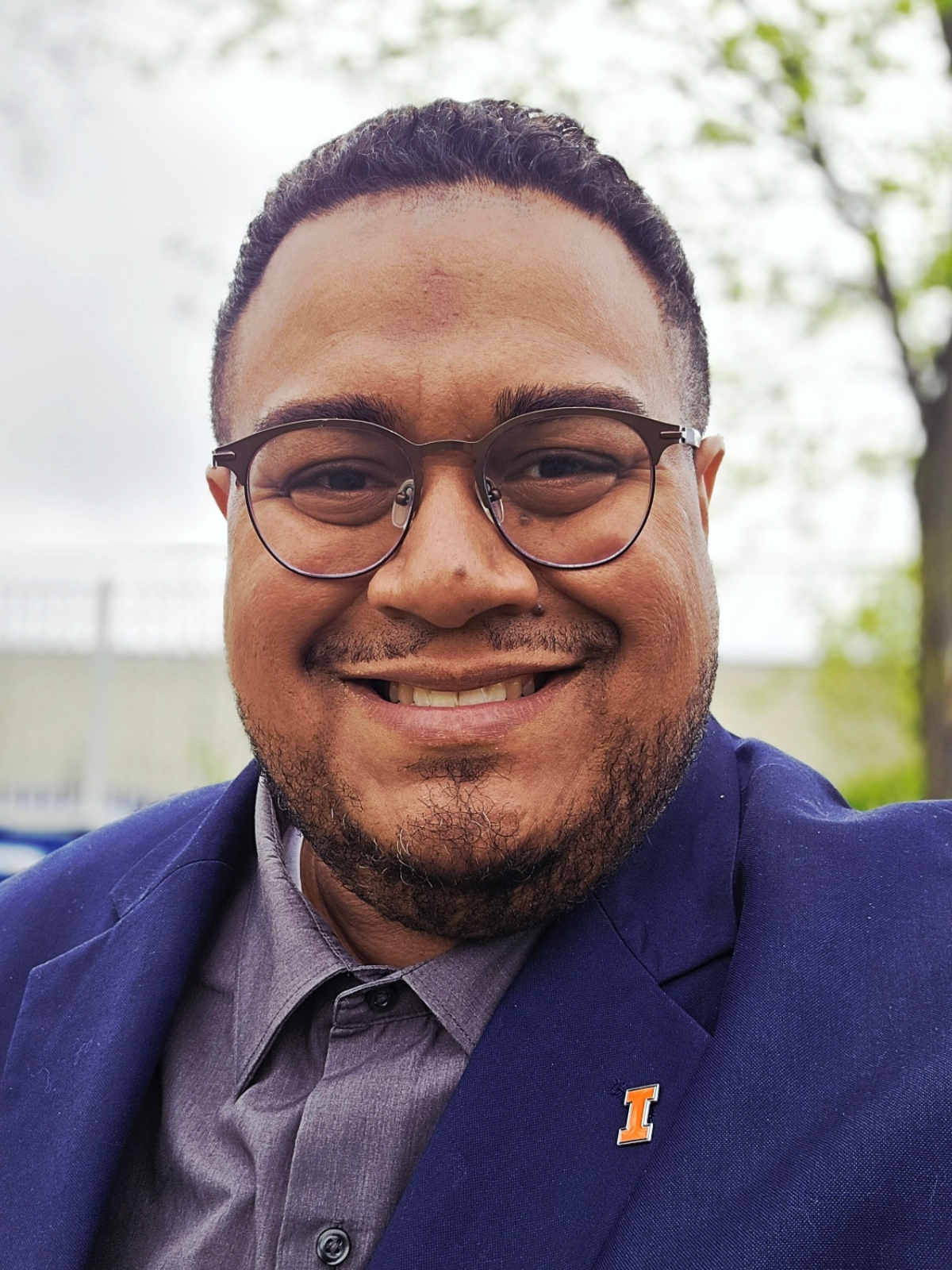 Dr. Angel L. Velez outdoors in Chicago, wearing a navy blazer with a University of Illinois pin