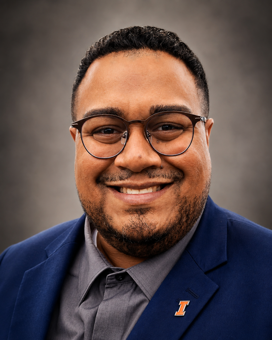 Studio portrait of Dr. Angel L. Velez in a navy blazer with a University of Illinois pin